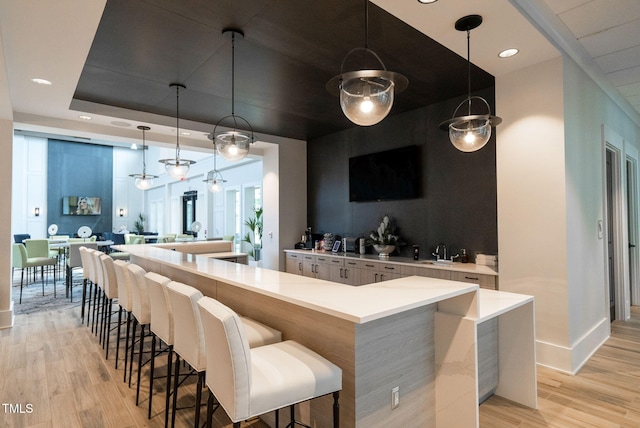 bar with light hardwood / wood-style flooring, sink, and hanging light fixtures