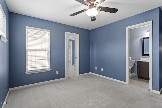 unfurnished bedroom featuring light colored carpet, ceiling fan, and ensuite bath