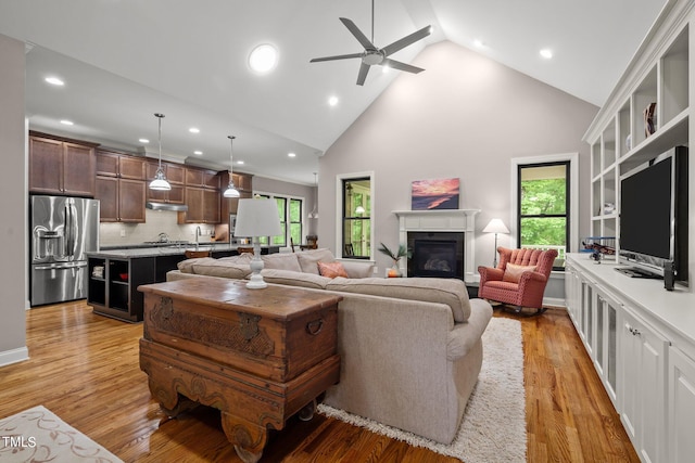 living room with light hardwood / wood-style flooring, high vaulted ceiling, a healthy amount of sunlight, and ceiling fan