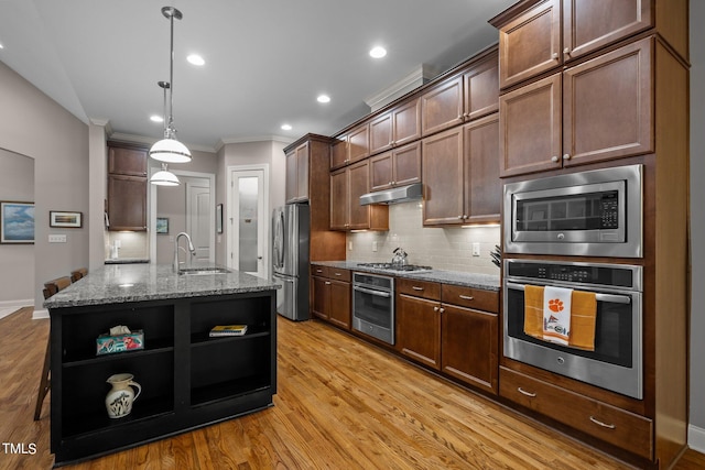 kitchen with a kitchen island with sink, light hardwood / wood-style flooring, sink, light stone countertops, and appliances with stainless steel finishes