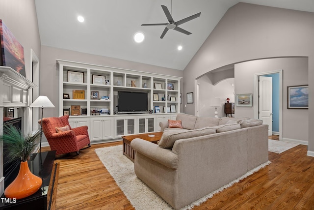 living room with ceiling fan, high vaulted ceiling, and light wood-type flooring