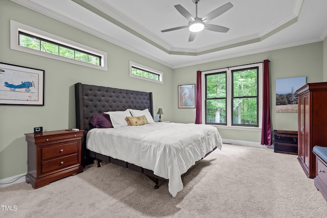 bedroom featuring ceiling fan, crown molding, a tray ceiling, and light colored carpet