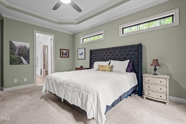 carpeted bedroom with ensuite bath, ornamental molding, a tray ceiling, and ceiling fan