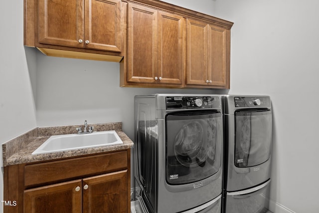 clothes washing area with cabinets, washer and dryer, and sink