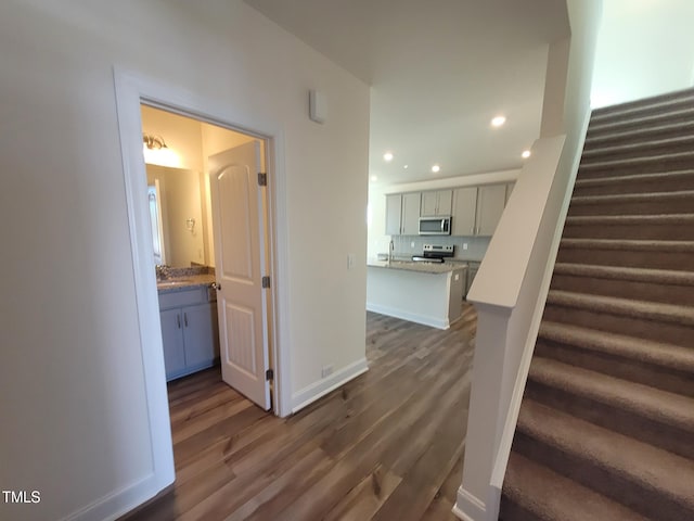 stairs featuring wood finished floors, recessed lighting, and baseboards