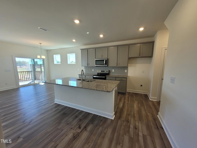 kitchen featuring stainless steel appliances, a sink, gray cabinets, dark wood finished floors, and recessed lighting