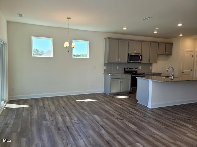 kitchen with appliances with stainless steel finishes, gray cabinetry, a sink, dark wood-style floors, and recessed lighting
