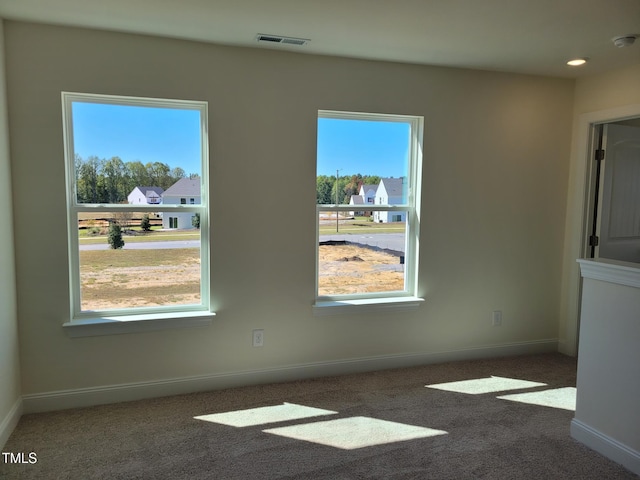 carpeted empty room featuring plenty of natural light, baseboards, and a smoke detector