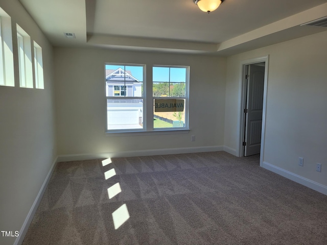 unfurnished room with a tray ceiling, carpet, and baseboards