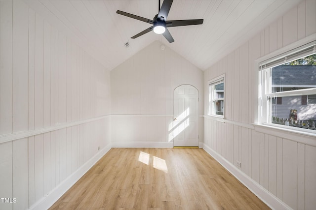 empty room featuring light hardwood / wood-style floors, wood walls, and lofted ceiling