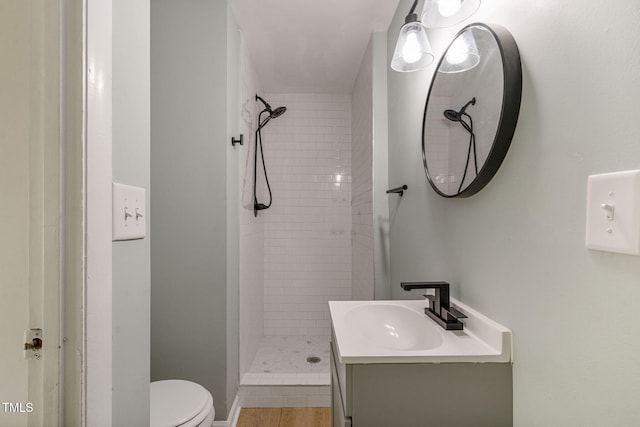 bathroom featuring a tile shower, toilet, vanity, and tile patterned flooring