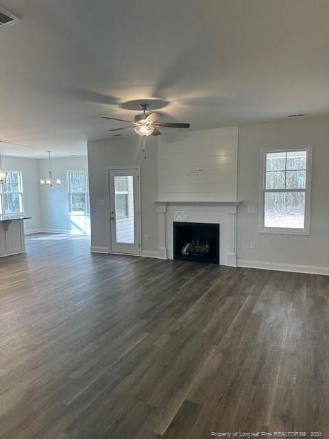 unfurnished living room featuring dark hardwood / wood-style flooring and ceiling fan with notable chandelier