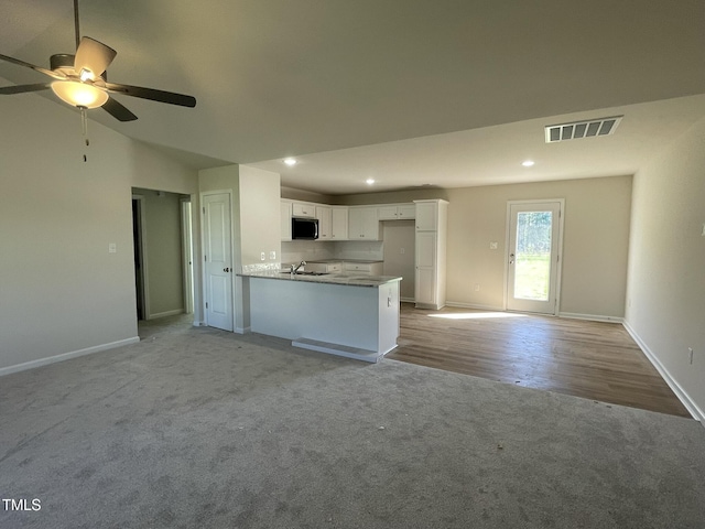 108 Pate Landing Dr, Selma, NC 27576 - kitchen featuring visible vents, white cabinets, a sink, stainless steel microwave, and light colored carpet