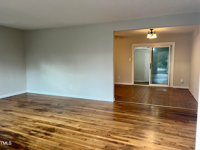 unfurnished room featuring a chandelier and hardwood / wood-style flooring