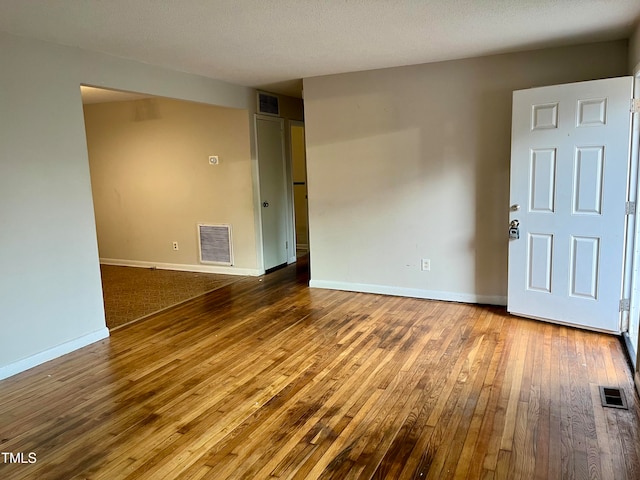 unfurnished room with hardwood / wood-style floors and a textured ceiling