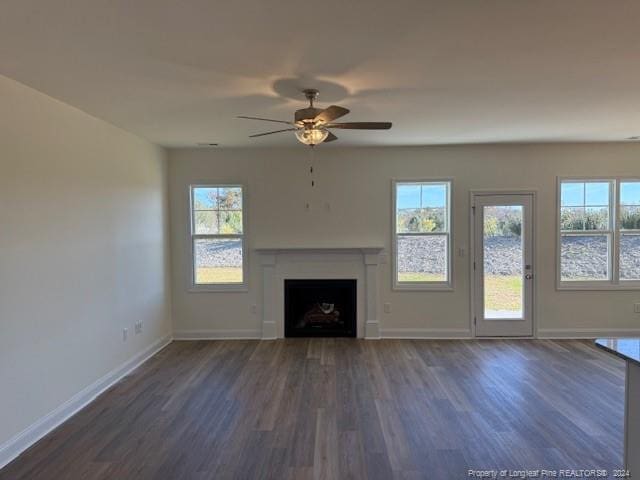 unfurnished living room featuring dark wood-type flooring and ceiling fan