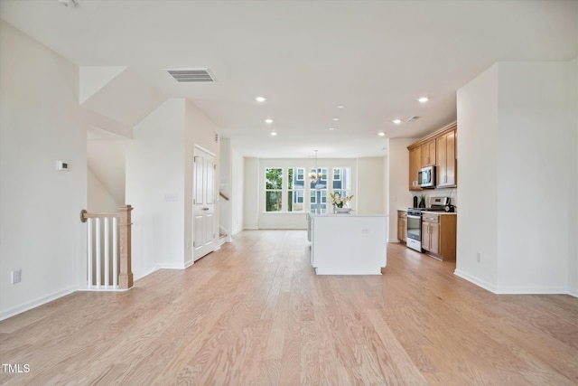 kitchen with stainless steel appliances, a kitchen island, and light hardwood / wood-style flooring