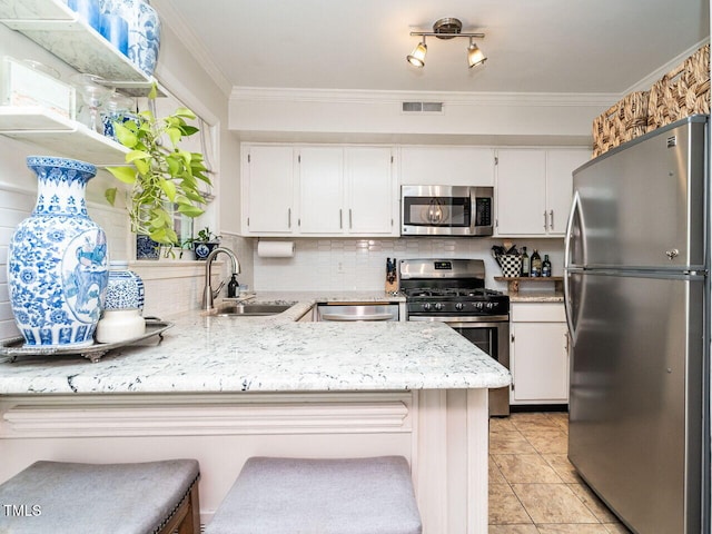 kitchen with a breakfast bar, appliances with stainless steel finishes, kitchen peninsula, and white cabinetry