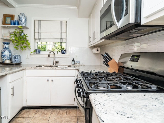 kitchen with a sink, stainless steel appliances, ornamental molding, decorative backsplash, and white cabinets
