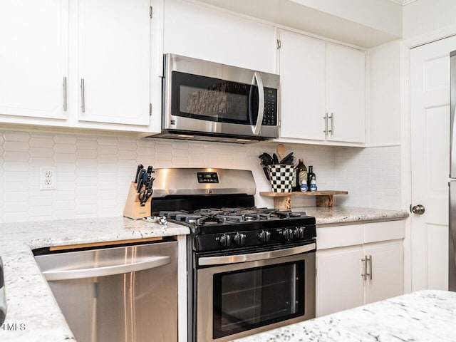 kitchen with decorative backsplash, appliances with stainless steel finishes, light stone counters, and white cabinets