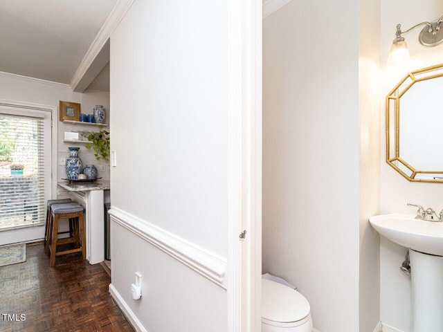 bathroom with toilet, crown molding, parquet floors, and sink