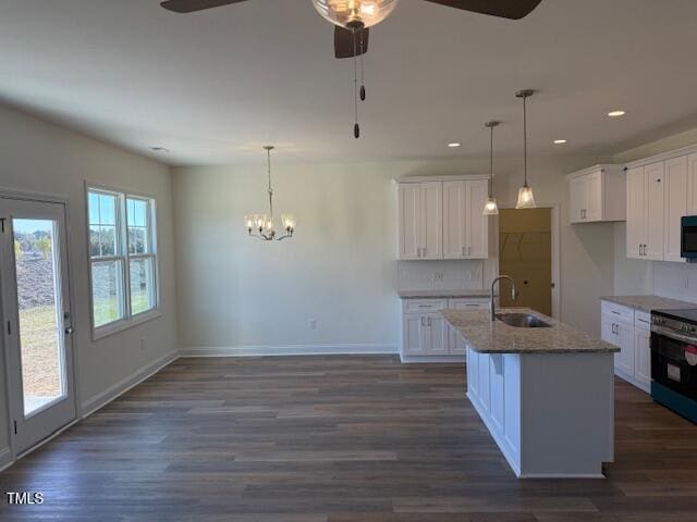 kitchen with dark hardwood / wood-style flooring, white cabinets, hanging light fixtures, and a kitchen island with sink