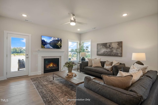 living room featuring a glass covered fireplace, a ceiling fan, recessed lighting, wood finished floors, and visible vents