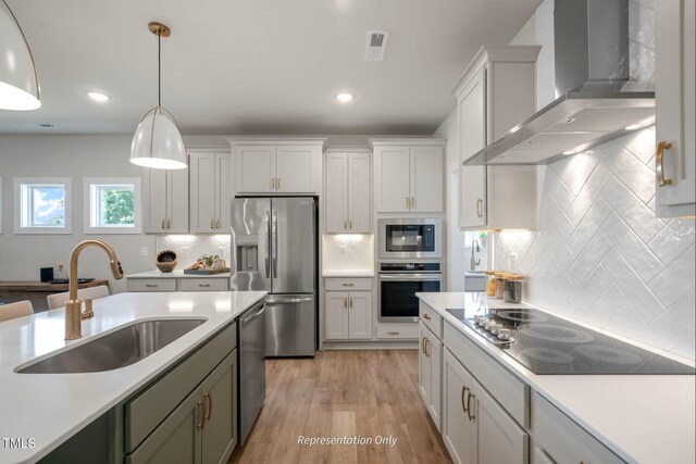 kitchen with wall chimney range hood, a sink, black appliances, and light countertops