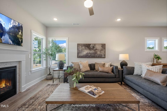 living area featuring visible vents, a glass covered fireplace, wood finished floors, recessed lighting, and a ceiling fan
