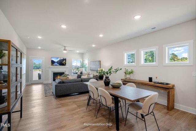 dining space with a glass covered fireplace, a ceiling fan, recessed lighting, and visible vents