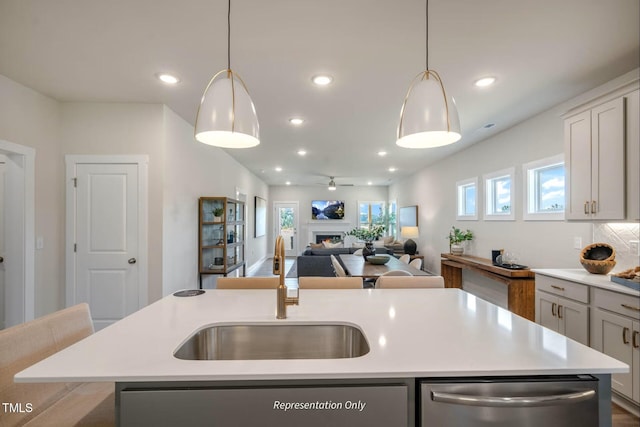 kitchen with a center island with sink, dishwasher, a sink, light countertops, and open floor plan