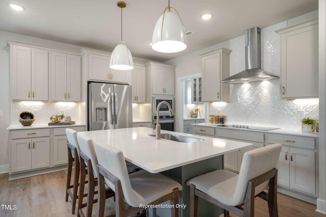 kitchen featuring wall chimney range hood, a sink, stainless steel fridge with ice dispenser, wood finished floors, and tasteful backsplash