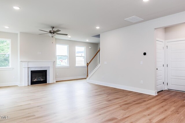 240 Fast Pitch Ln, Four Oaks, NC 27524 - unfurnished living room featuring light wood-style floors, a ceiling fan, a premium fireplace, stairs, and baseboards