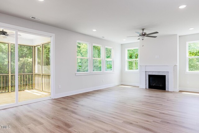unfurnished living room featuring ceiling fan, light wood-style flooring, baseboards, a fireplace, and recessed lighting