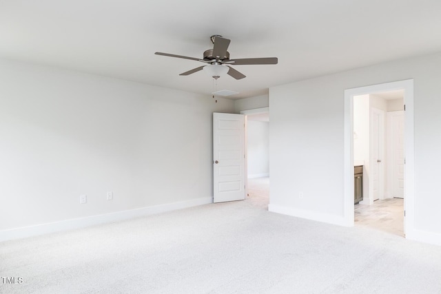 unfurnished bedroom featuring light colored carpet, baseboards, ensuite bathroom, and a ceiling fan