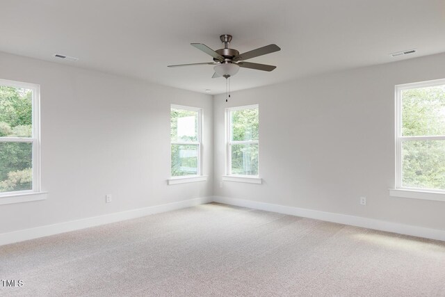 spare room with baseboards, healthy amount of natural light, ceiling fan, and light colored carpet