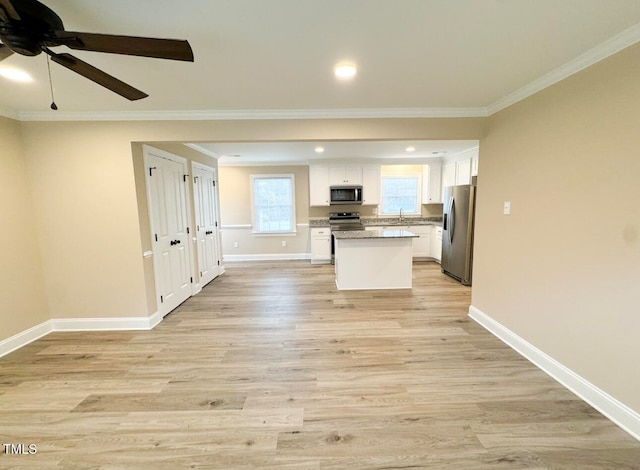 kitchen featuring a kitchen island, crown molding, white cabinets, appliances with stainless steel finishes, and light hardwood / wood-style floors