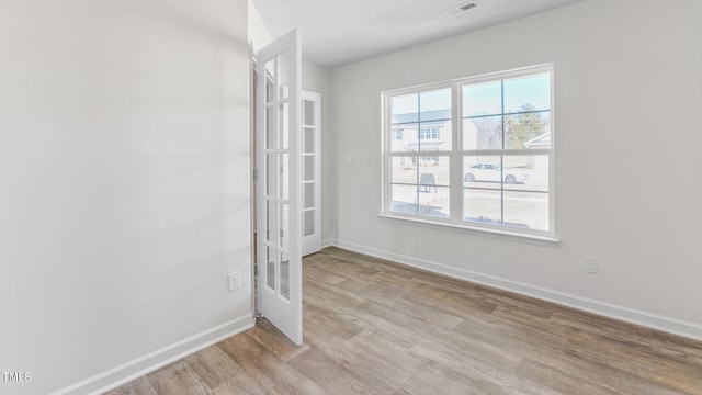 unfurnished room with french doors and light hardwood / wood-style floors