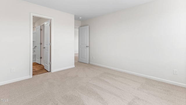 unfurnished bedroom featuring light carpet and ensuite bath