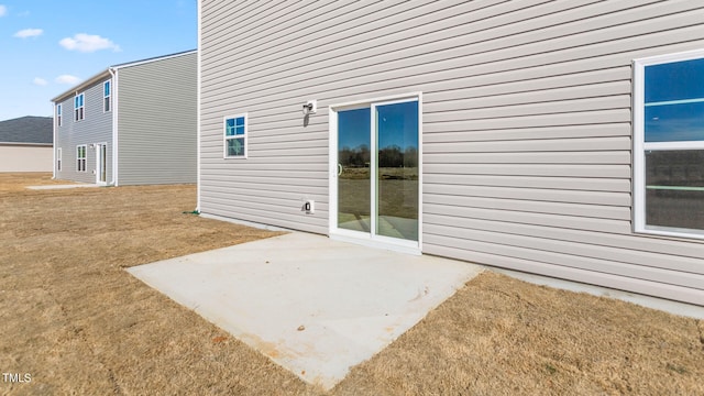 view of side of property with a patio area and a lawn