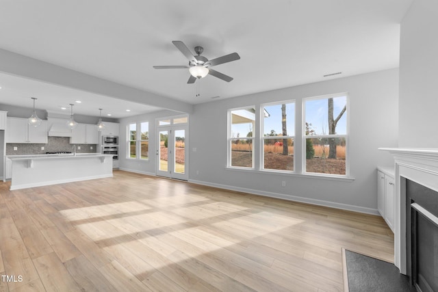 unfurnished living room with ceiling fan and light hardwood / wood-style floors