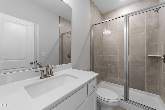 bathroom with vanity, toilet, and a shower with door