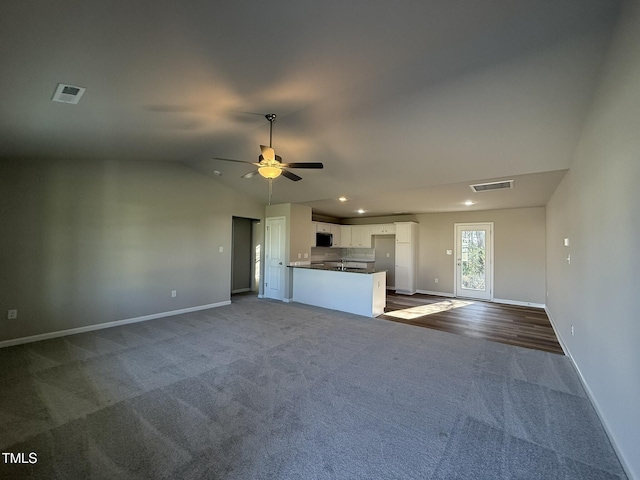 unfurnished living room featuring visible vents, baseboards, a ceiling fan, lofted ceiling, and dark carpet