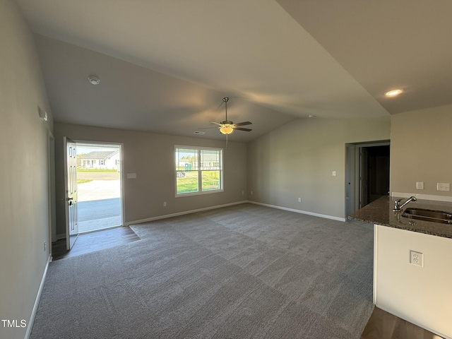 unfurnished living room featuring a ceiling fan, a sink, carpet, and lofted ceiling