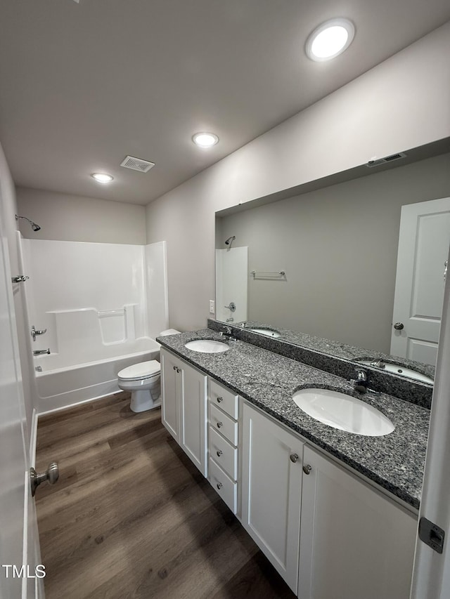 bathroom featuring wood finished floors, a sink, double vanity, and visible vents