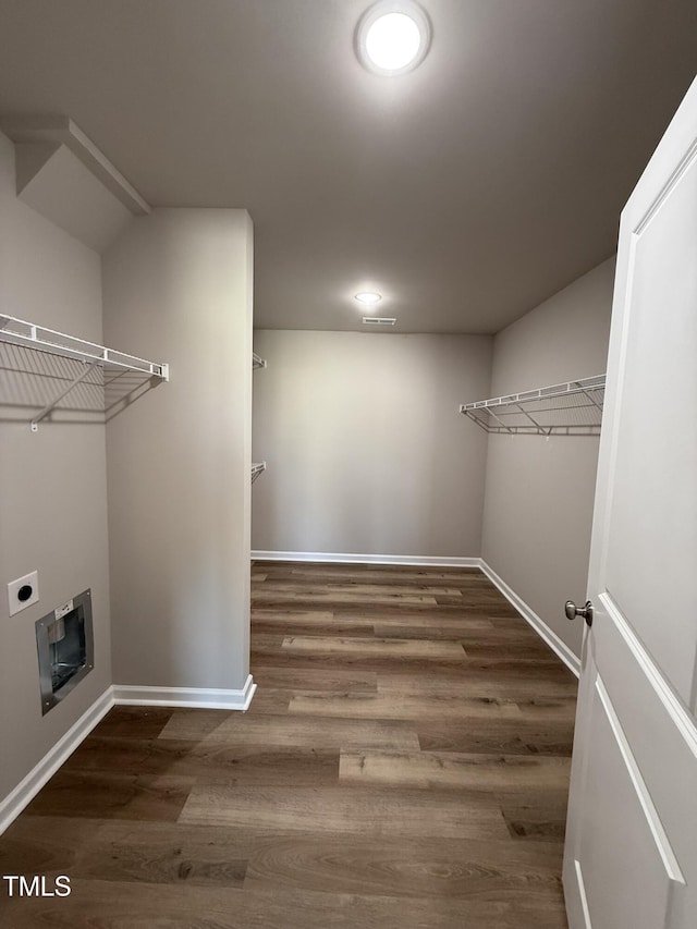 laundry room with baseboards, wood finished floors, laundry area, heating unit, and hookup for an electric dryer