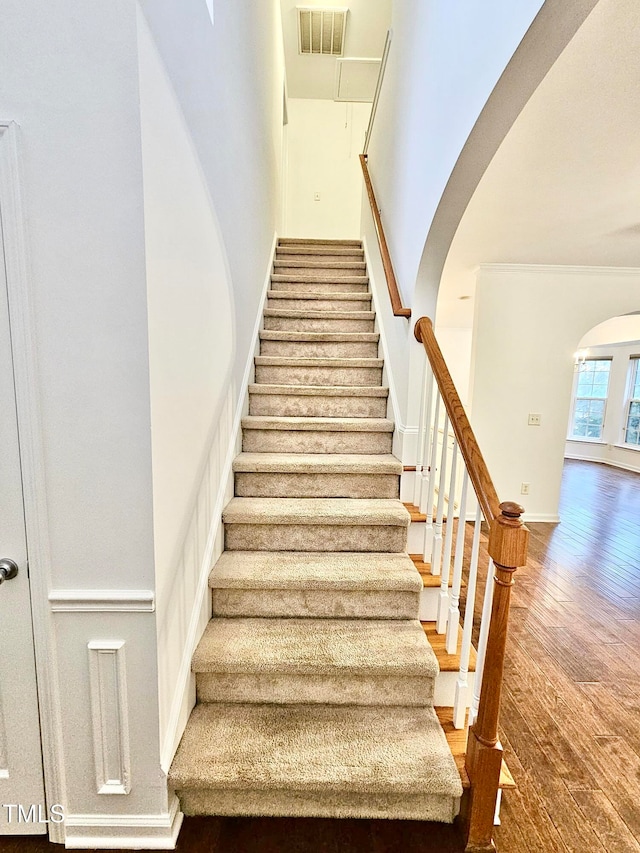 staircase with a towering ceiling and hardwood / wood-style flooring