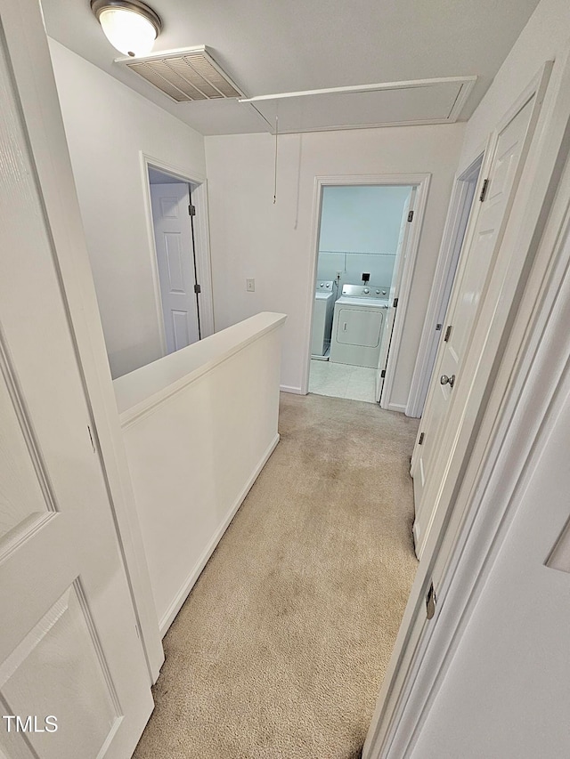 corridor with light colored carpet and independent washer and dryer