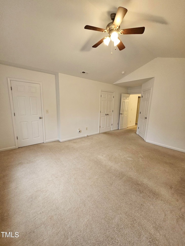 carpeted spare room with ceiling fan and vaulted ceiling