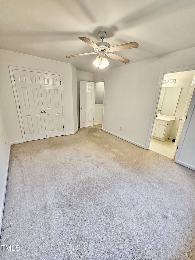 unfurnished bedroom featuring ensuite bath, ceiling fan, a closet, and light carpet